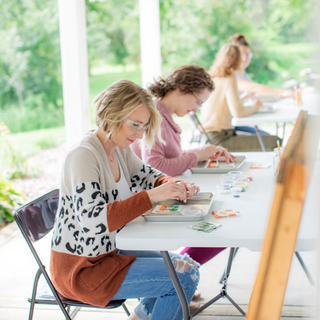 Students working on a glass fusing project outside on the porch at The Glass Orchard