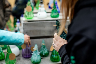 Woman holding a glass tree in front of a display of glass trees