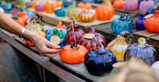 Hand reaching out to a display with glass pumpkins