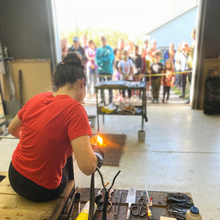 Live glass blowing demonstration. Instructor shaping glass in front of audience.