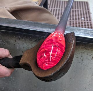 Molten glass being shaped by a tool