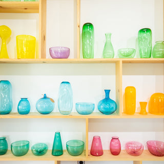 Shelf display of glass art projects, vases and bowls 