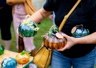 Three glass pumpkins being held by one customer