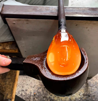 Molten glass being shaped with a tool