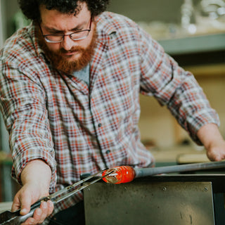 Glass artist working with equipment to form glass art 