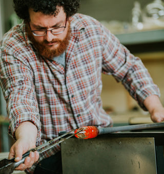 Glass artist working with equipment to form glass art 